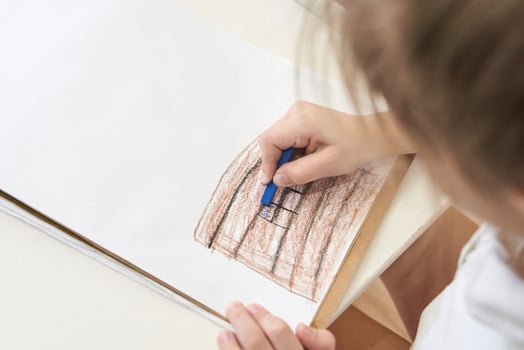 Caucasian child drawing with crayon on paper at home, focusing on creativity and art skills development. photo