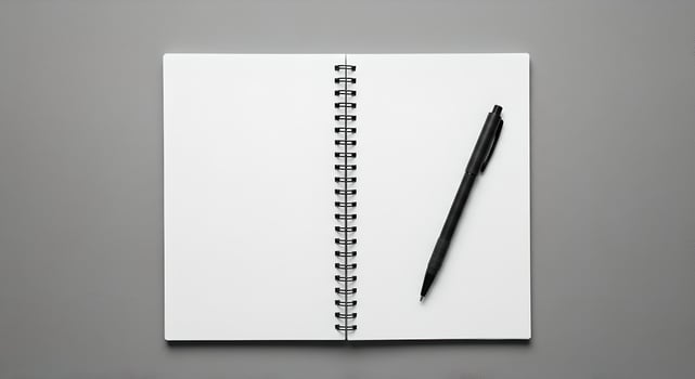 Spiral notebook with black pen on smooth monochrome surface, softly lit. photo