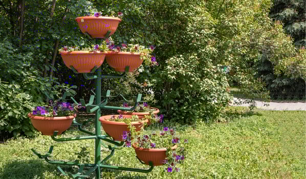 A beautiful multi-tiered metal stand for flower pots, in a park, outdoors photo