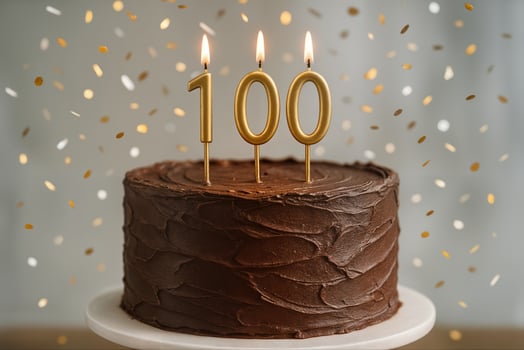Chocolate Cake with Gold 100 Candles and Confetti for Century Celebration and Milestone Event photo