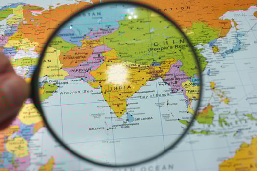 Exploring India on a colorful world map with a magnifying glass highlighting its location among neighboring countries photo