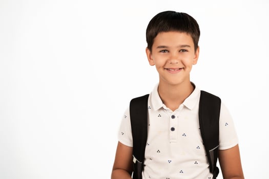 Young boy with short dark hair wearing a white polo shirt and black backpack, isolated on a white background. Suitable for educational, back to school, or youth-related concepts. photo