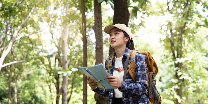 Young Woman with Map Gazing Up in Forest photo