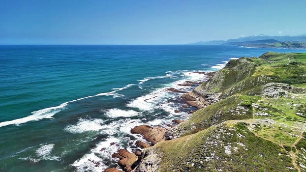 The stunning coastal landscape has sparkling turquoise waters and lush green cliffs that captivate photo