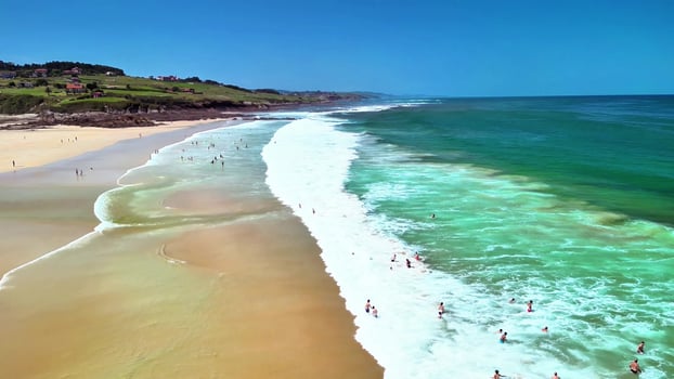 A stunning aerial view captures a beautiful sunny beach filled with surfers enjoying clear water photo