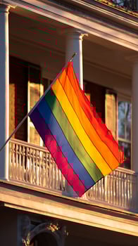Rainbow Flag Flying High at Sunset on a Classic Building Balcony. photo