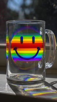 Rainbow Smiley Face Mug Captures Sunlight and Joyful Reflections. photo