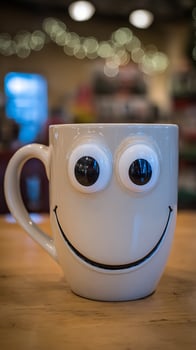 A Cheerful Coffee Mug With Big Googly Eyes Smiling on a Table. photo