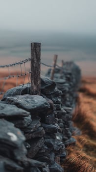 Rustic Stone Wall and Barbed Wire Fence in a Moody Landscape. photo