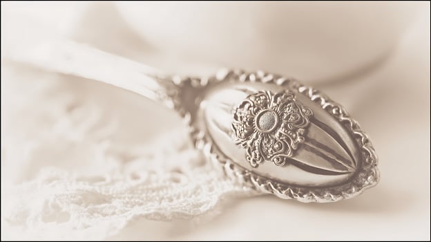 Ornate Silver Spoon Resting on Delicate White Lace. photo