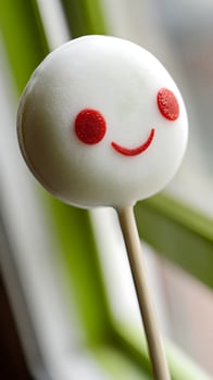 Adorable Smiley Face Cake Pop Against a Blurry Green Background. photo