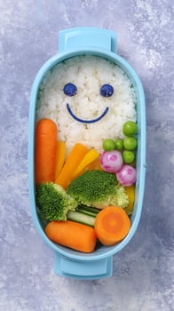 Fun smiley face bento box with healthy vegetables and rice for kids. photo