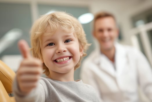 smiling child in dental chair giving thumbs up, photo
