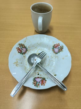 Dirty plates after being used for eating with crossed spoons and forks and a mug next to them. photo