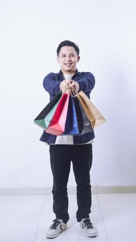 Full length photo of happy Asian man with many shopping bags isolated on white background