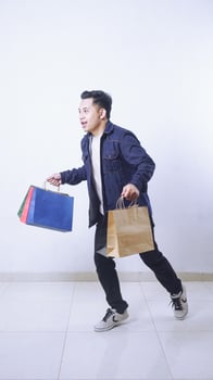 Full length photo of Asian man carrying shopping bags rushing next store isolated on white background