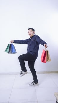Full length photo of Asian man carrying many shopping bags with excitement isolated on white background