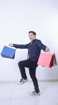 Full length photo of Asian man carrying many shopping bags with happiness isolated on white background