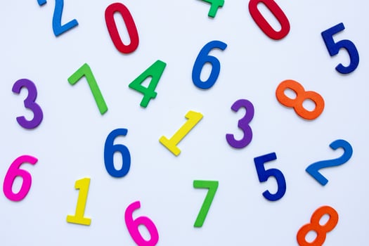 Colorful wooden numbers scattered on white background photo