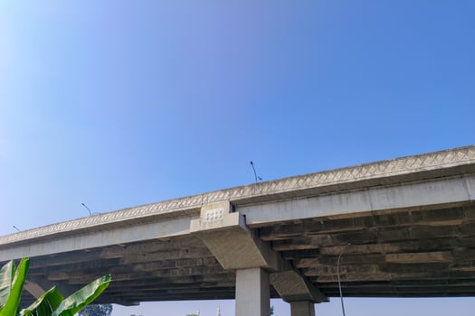 Concrete bridge structure viewed from below against a clear blue sky. photo