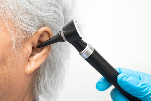 Otolaryngologist or ENT physician doctor examining senior patient ear with otoscope, hearing loss photo