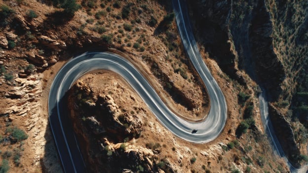 Serpentine Road Curves Through Rocky Terrain in Desert Landscape Captured From Above photo