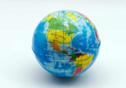 A brightly colored miniature world globe showing north and south america on a clean white backdrop, ideal for educational concepts. photo