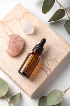 Amber dropper bottle with rose quartz and eucalyptus leaves on marble photo
