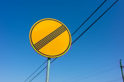 A yellow road sign displaying the end of restriction against a clear blue sky photo