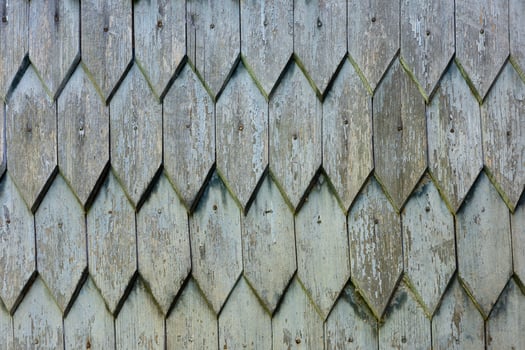 Weathered wooden shingles create an aged, textured diamond pattern on a building. photo