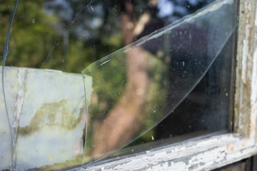 Close up of a broken window, showcasing the shattered glass and peeling paint. photo