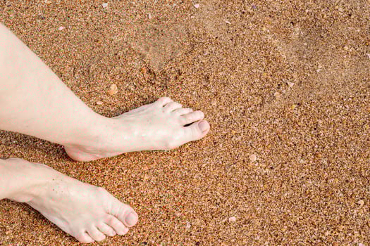 Bare feet standing on a sandy beach capturing a simple moment of relaxation and unity with nature, copy space photo