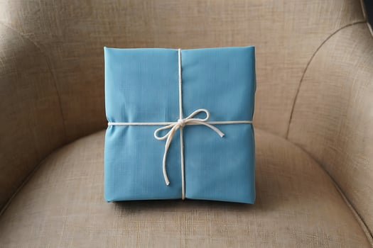 A neatly wrapped gift in blue fabric tied with white twine sits on a textured surface photo