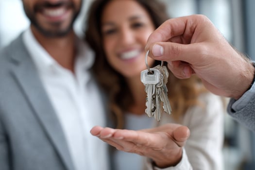 Close up of real estate agent giving house keys to happy couple. New property owners, american dream photo