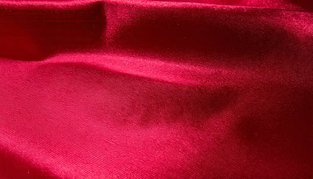 Close-up of a deep red, shiny silk fabric texture as a background photo