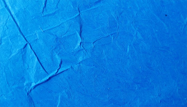 Close-up of a vibrant electric blue paper surface with intricate blue patterning as a background photo