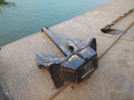 Rusty ship's anchor and mast chain on iron ground photo