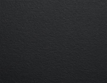 Close-up of a black, coarse-textured paper surface with a patterned background photo