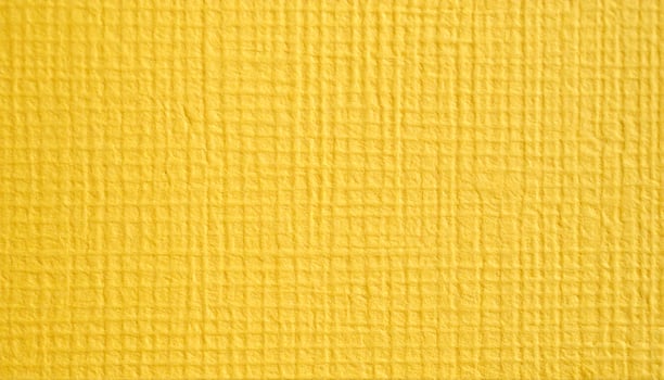 Close-up of a rough yellow paper surface with a textured pattern background photo