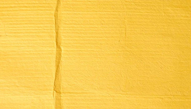 Close-up of a yellow, coarse-textured paper surface with a patterned background photo
