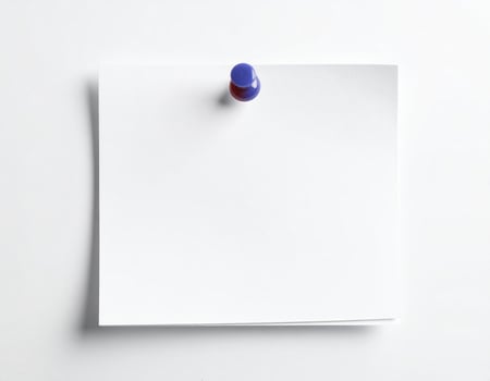 A white notepad with a thumbtack placed on it against a plain white backdrop photo