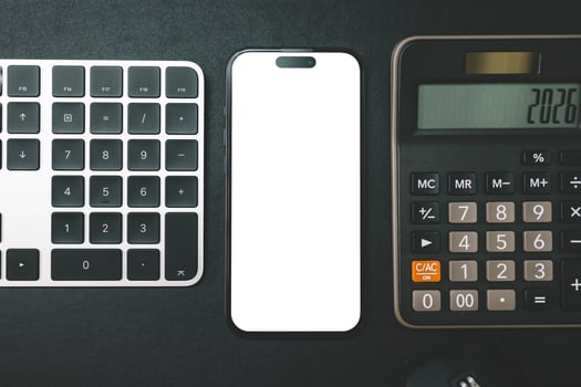 Hand Holding Blank Smartphone with Keyboard and Calculator. Perfect for showcasing mobile apps or web designs against a blurred keyboard background. photo