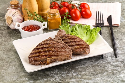 Grilled steak on a plate with tomatoes, lettuce and ketchup photo