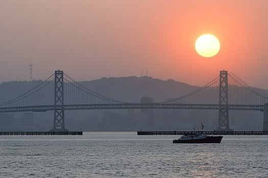The sun sets behind the bay bridge in san francisco photo