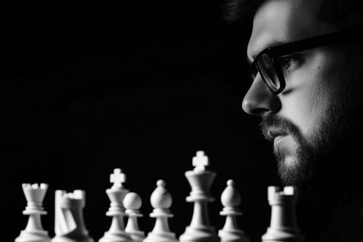 A man in glasses and a beard is playing chess photo