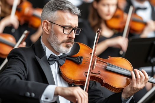A man in a suit playing the violin in front of an orchestra photo