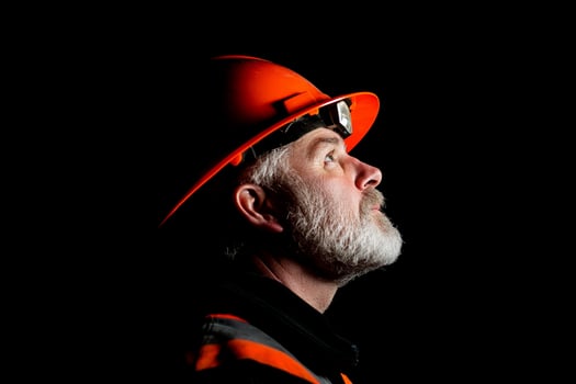 A man in an orange hard hat looking up photo