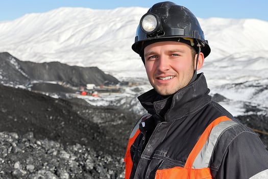 A man in a hard hat standing in front of a mountain photo
