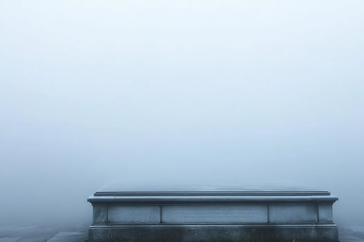 A tombstone sits in the fog on a sidewalk photo