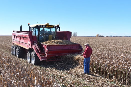 A man standing in a field with a tractor photo